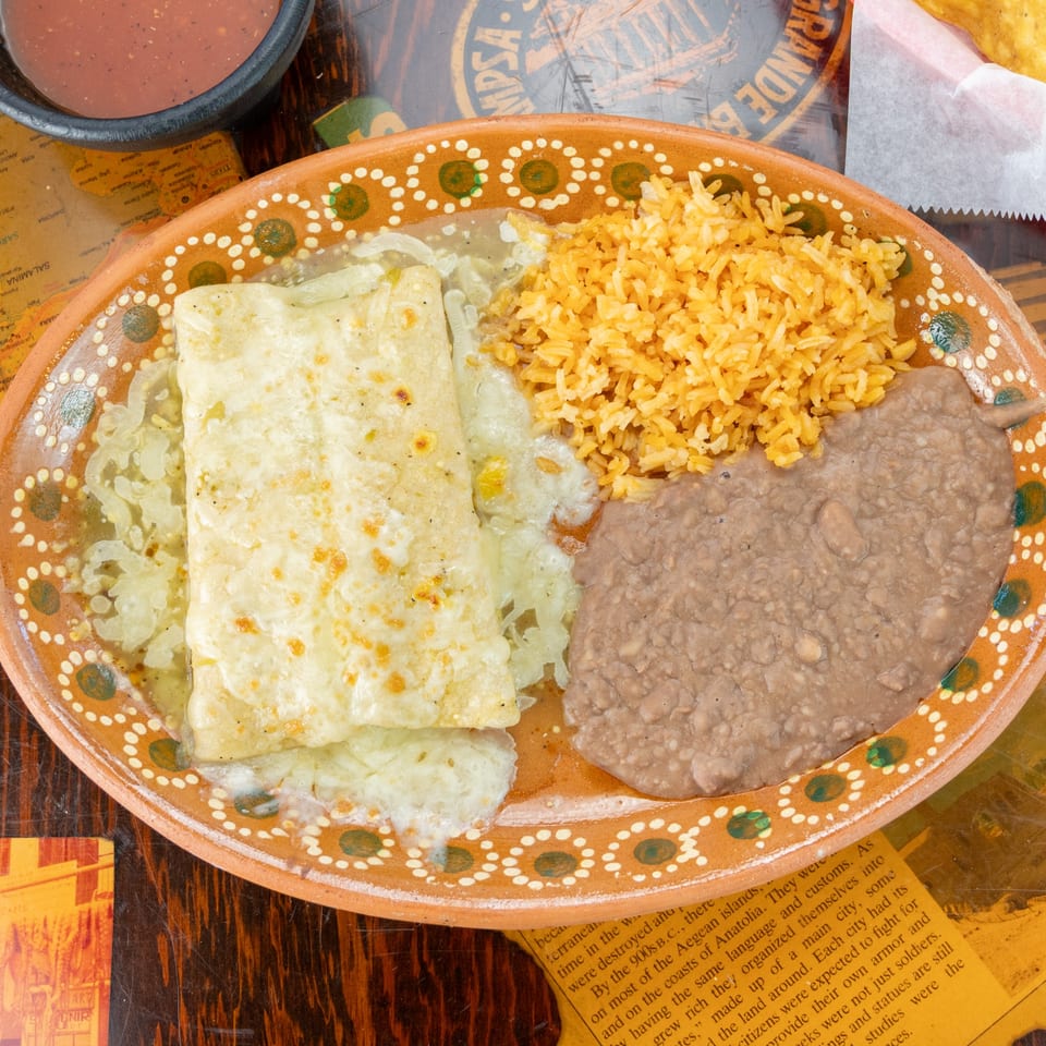 Los Vega Mexican Restaurant's enchiladas with rice and refried beans on a decorative orange plate.