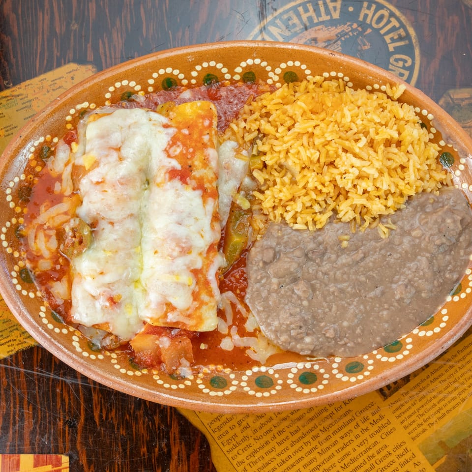 Los Vega Mexican Restaurant's enchiladas with rice and refried beans on a decorative plate.